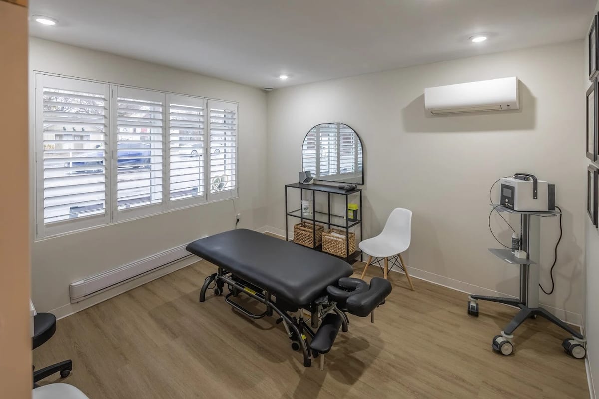 A treatment room at DC Chiropractic, with the adjusting table, shuttered windows and therapy equipment